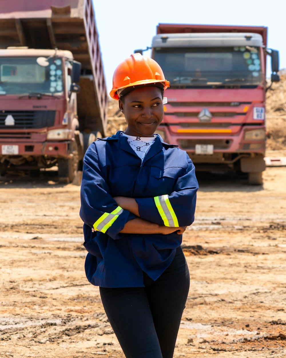An engineer in a hard hat standing in front of mining trucks