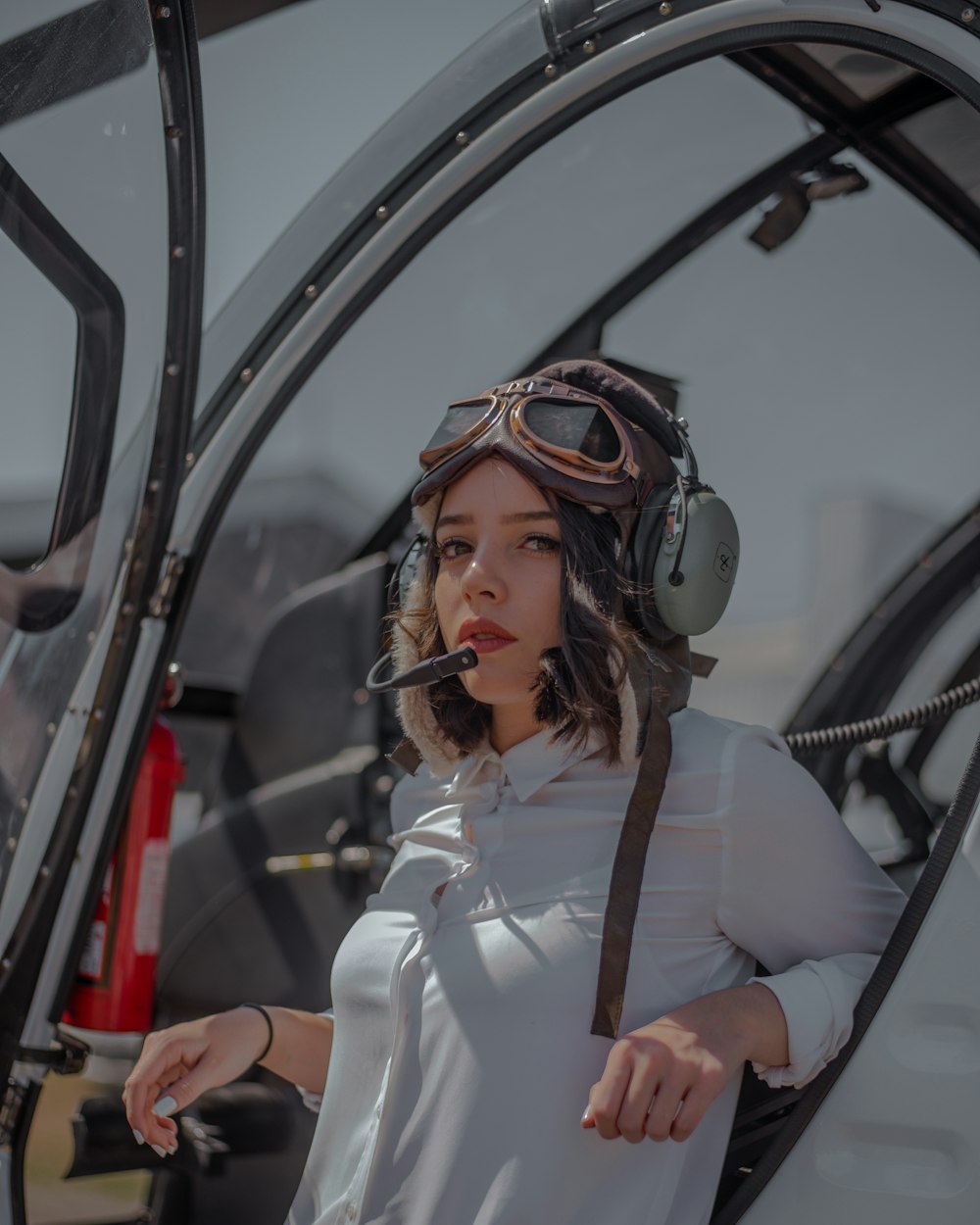 A pilot in a leather flying helmet in the cockpit