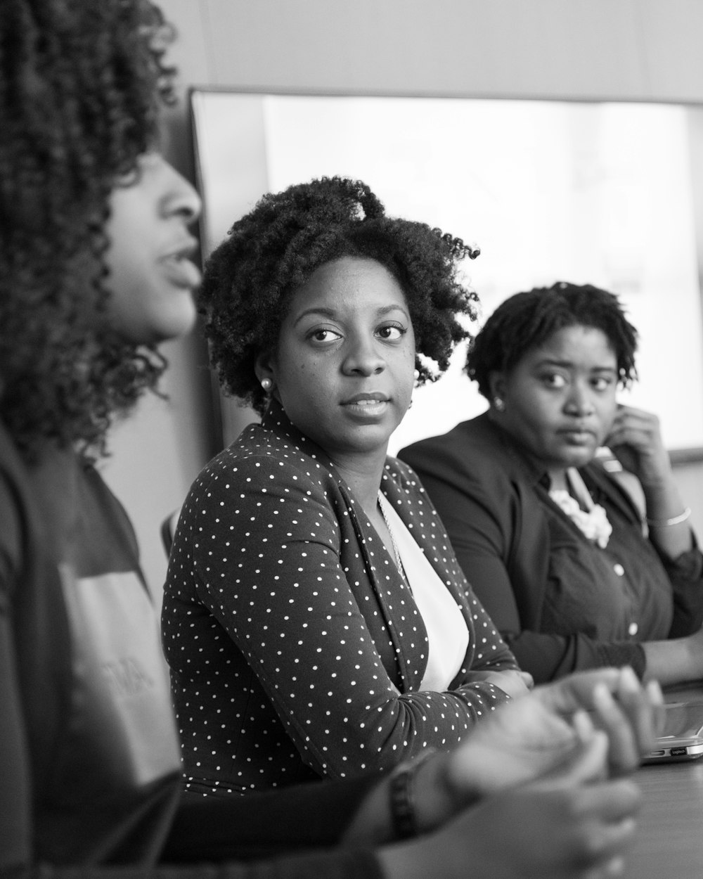 Women around a conference table listening to a colleague